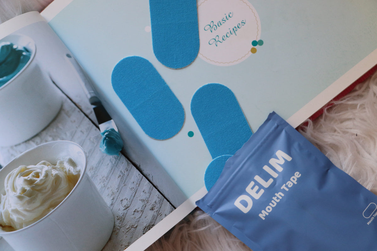 Blue DELIM mouth tape package with a recipe book and dessert in the background